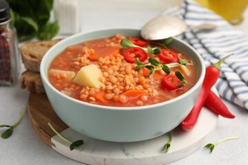 Delicious lentil soup with vegetables served on light grey table, closeup