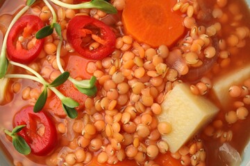 Delicious lentil soup with vegetables as background, top view