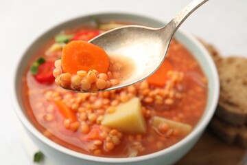 Eating delicious lentil soup at table, closeup