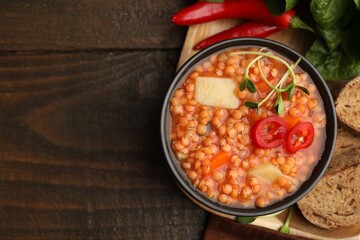 Delicious lentil soup with vegetables served on wooden table, flat lay. Space for text