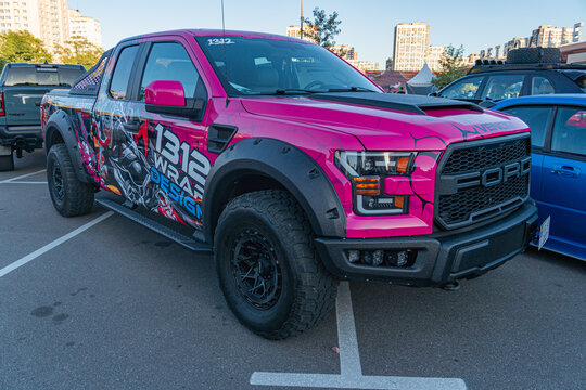 A vibrant pink Ford F-150 pickup truck, adorned with racing decals is parked on a concrete floor in an outdoor parking area The photograph is realistic and capture - Kyiv, Ukraine - September 21, 2025