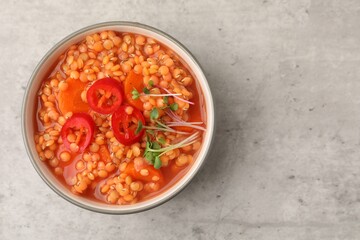 Delicious lentil soup with vegetables in bowl on grey table, top view. Space for text