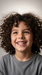 Happy young boy with cute curly hair smiling broadly and looking up isolated on white background