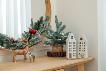 Mirror and Christmas decor on console table near white wall indoors