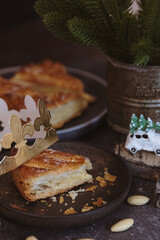 One bitten piece of galette in a plate with a toy on a dark table.