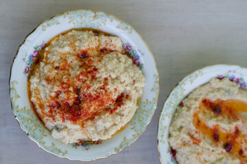 Creamy homemade hummus served in antique ceramic bowls garnished with paprika and olive oil drizzle on a rustic wooden table. Top viwe