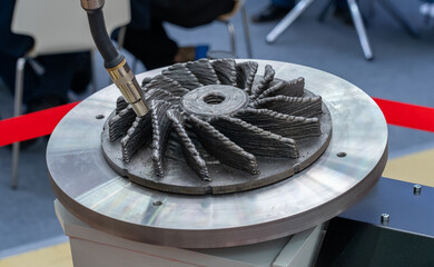 Robotic arm using advanced metal additive manufacturing to precisely build complex, textured turbine-like component on circular platform, highlighting industrial 3D printing technology