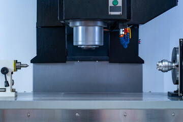 Close-up of modern industrial CNC precision machining equipment showing spindle, work holding devices, and slotted table in manufacturing workshop environment