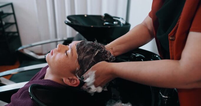 Happy boy, relax and washing with hair in salon above for grooming, spa or haircare treatment. Top view, child or customer with hairdresser, shampoo or soap for cleaning or massage in beauty parlor