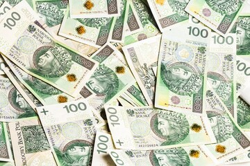 A vibrant spread of Polish 100-zloty banknotes arranged in a scattered pattern, showcasing detailed...