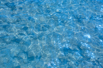 Clear turquoise water surface with shimmering reflections, showcasing the beauty of nature and aquatic life beneath, creating a tranquil and serene atmosphere for relaxation