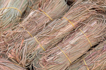 Bundles of dried grass tied with yellow bands, showcasing natural textures and colors, arranged in a neat pile, representing agricultural products and traditional craftsmanship