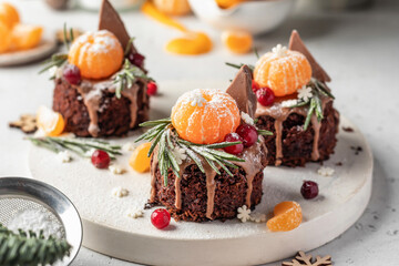 Chocolate brownie cakes with festive decor with tangerines on white kitchen table. Christmas or New Year food ideas sweet homemade pastry concept. Holiday cooking