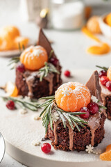Chocolate brownie cakes with festive decor with tangerines on white kitchen table. Christmas or New Year food ideas sweet homemade pastry concept. Holiday cooking