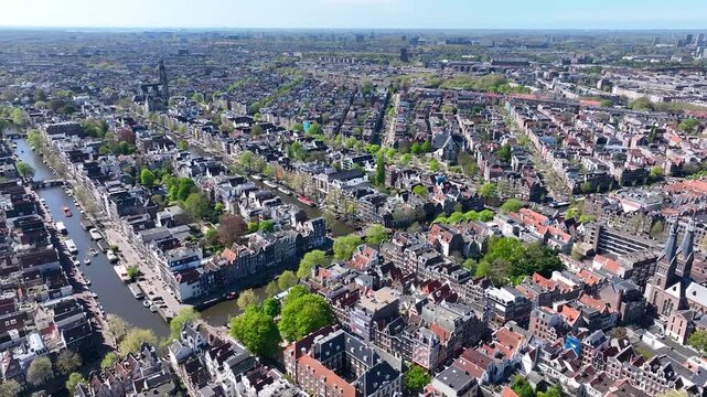 Beautiful aerial drone view from above, Amsterdam,  Netherlands. Narrow canals with bridges, street, boats, architectures lines of houses, famous sights and traffic around city downtown in Holland.4K