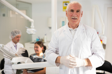 Obraz premium Mature man dentist posing while examining patient in dental clinic