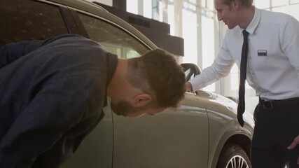 Side view shot of car salesman presenting big luxury car in dealership showroom and opening door inviting client for testing, copy space - Powered by Adobe