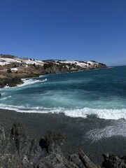 A scenic view of a rocky coastline with bright turquoise ocean waves and a clear blue sky. Natural coastal landscape ideal for travel, tourism, nature and adventure themes.