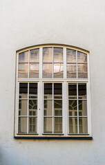 A large arched window with white framed panes reflects interior curtains. Ideal for architecture and interior design themes in Prague, Czech Republic.