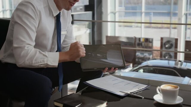 Close up shot of unrecognizable car salesman holding tablet and pointing at screen while explaining car specifications to client during consultation in dealership, copy space