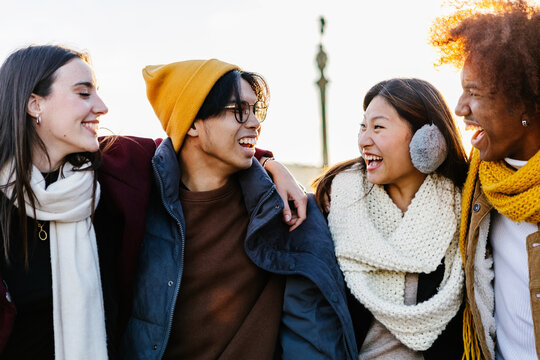 Diverse group of young friends having fun together outdoors on winter. Millennial student people laughing walking in city street enjoying day off. Youth community and friendship concept. - Powered by Adobe