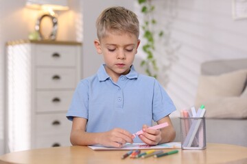 Cute little boy drawing at wooden table indoors