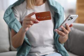 Woman making online payment with phone and credit card indoors, closeup