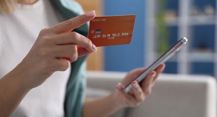 Woman making online payment with phone and credit card indoors, closeup