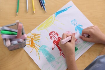 Cute little boy drawing family at wooden table indoors, closeup