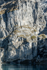 Obraz premium Tall Cliffs Catch Shadow And Light Over Oeschinen Lake