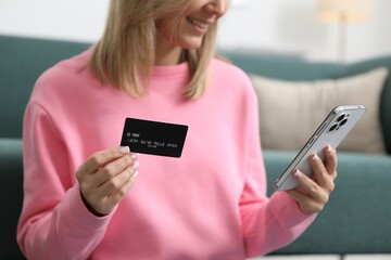 Woman making online payment with phone and credit card indoors, closeup