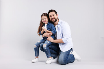 Happy father hugging his daughter on grey background. Family bonding