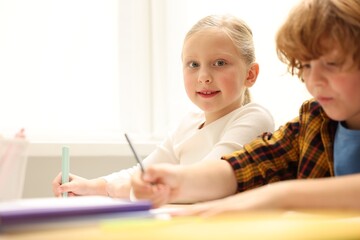 Happy children at desk in classroom. Space for text