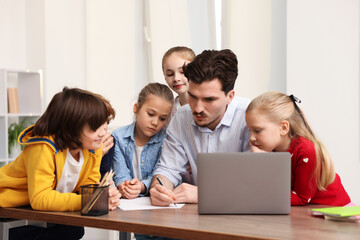 Fototapeta premium Teacher explaining exercise to students at desk in classroom