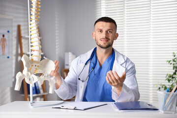 Doctor with human spine model in hospital