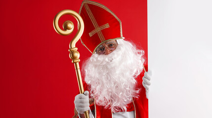 Saint Nicholas with crozier looking behind empty banner on red background