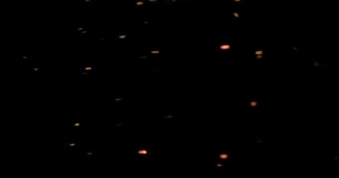 Red and golden particles shimmer in water against a dark background, reflecting warm light like cosmic dust&mdash;glowing, floating, glittering, universe-like atmosphere.