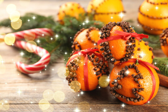 Fresh tangerines with cloves on white table, bokeh lights. Pomander balls