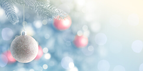 Christmas greeting card with festive ball hanging from fir tree branch and bokeh lights. Banner...