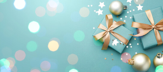 Christmas balls, gift boxes and confetti on turquoise background, top view. Greeting card design...