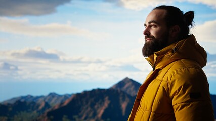 Hiker gazes at the panoramic view of dramatic mountain peaks and clouds, feeling the thrill of adventure and rewards of perseverance. The journey represents strength and personal growth. Camera A.