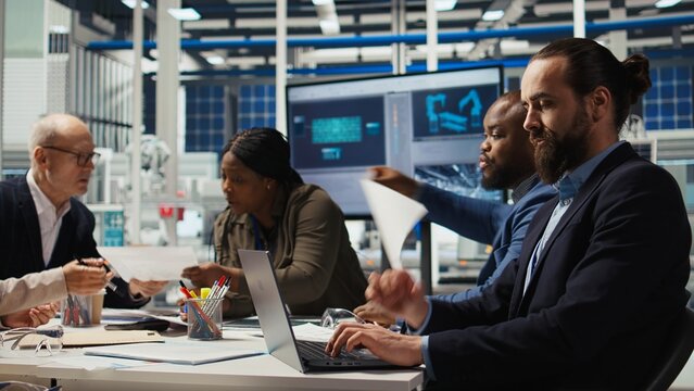 Industrial plant manager typing on laptop, preparing paperwork before business meeting. Factory executives working on pitch for investors using notebook, automating production, camera A