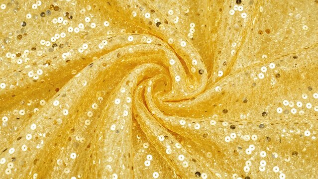 Golden fabric with swirling pattern and shiny sequins. Decorative material, luxury design. Fashion and craft, texture. The concept of elegance and glitz.