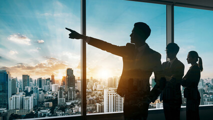朝日夕日の中の都市オフィスで進路を指し示すビジネスパートナーリーダーと従う従業員の選択した進む未来