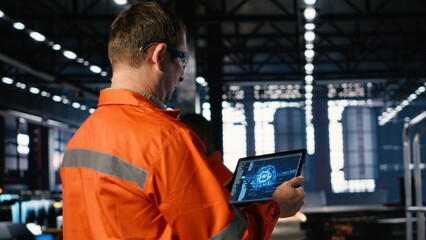 Worker using AI system powered by machine learning to monitor machinery on the factory floor,...