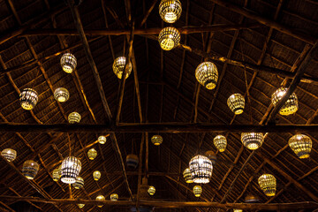 Rustic thatched roof illuminated by numerous glowing woven lanterns.