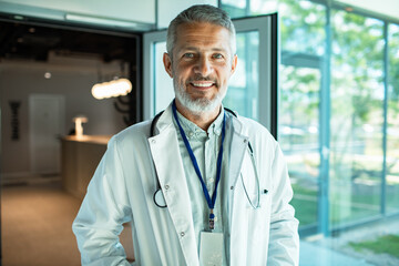 Mature male doctor smiling confidently in hospital corridor