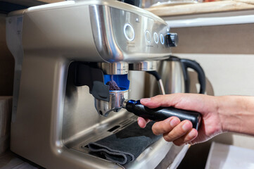 Barista preparing portafilter with coffee grounds using professional espresso machine