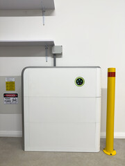 Vertical shot Solar electric battery storage unit in a garage on white wall green blue indicator lights
