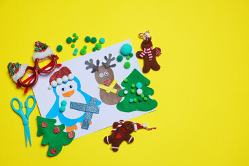 Child handmade craft. Christmas postcard, handicraft materials, funny glasses and scissors on yellow background, flat lay. Space for text